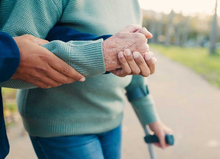 Family members meet with an older adult at a table to review care notes and share photographs.
